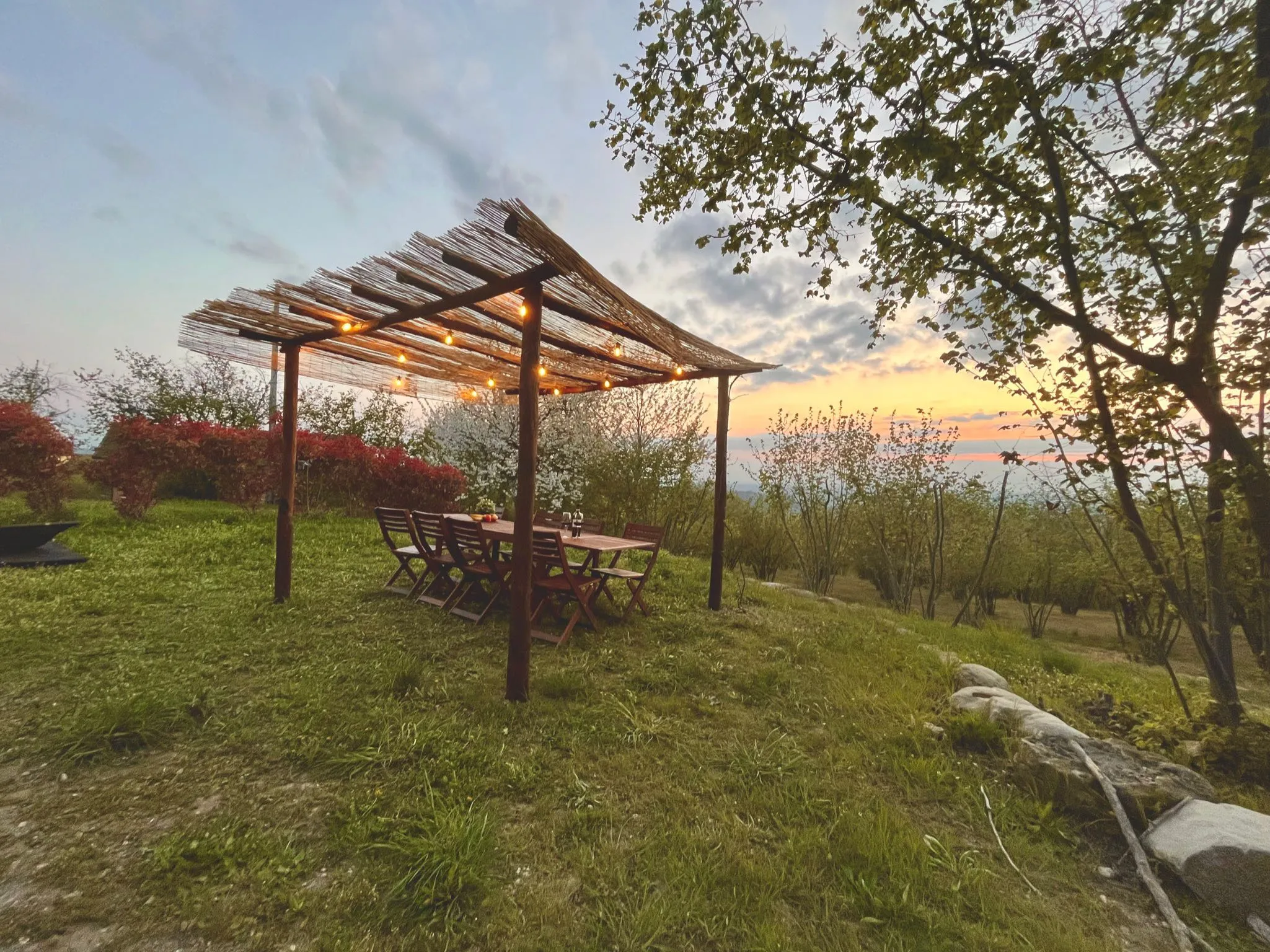 Pergola und Esstisch bei Sonnenuntergang, mit Lichterketten